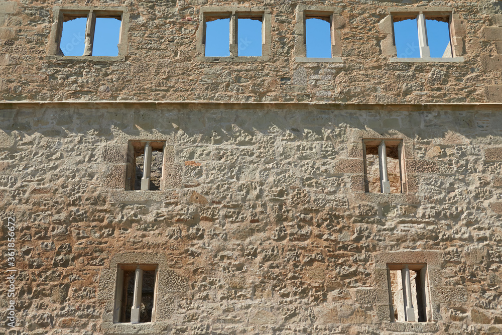 Facade of a brown castle wall, many beautiful windows to see, blue daylight. Germany.