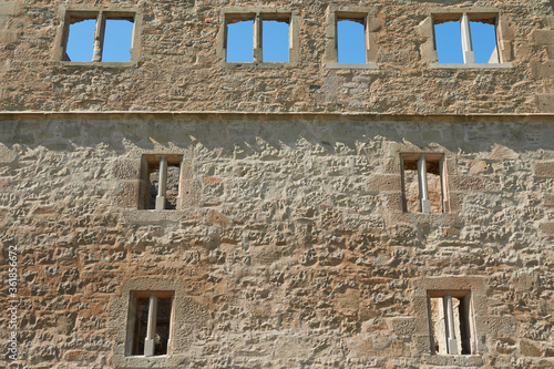 Facade of a brown castle wall, many beautiful windows to see, blue daylight. Germany. © Jan