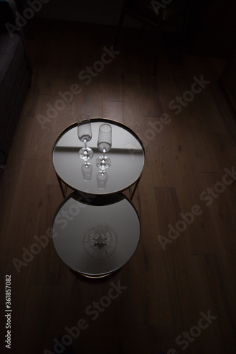 Two champane glasses in mirror coffe table in dark room with oak wood floor photo