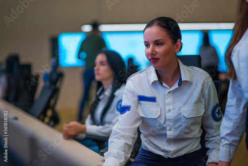 Security guard monitoring modern CCTV cameras in a surveillance room. Female security guards sitting having conversation monitoring cctv.