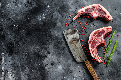 raw lamb chops fresh cut with meat cleaver. Black background. Top view. Copy space