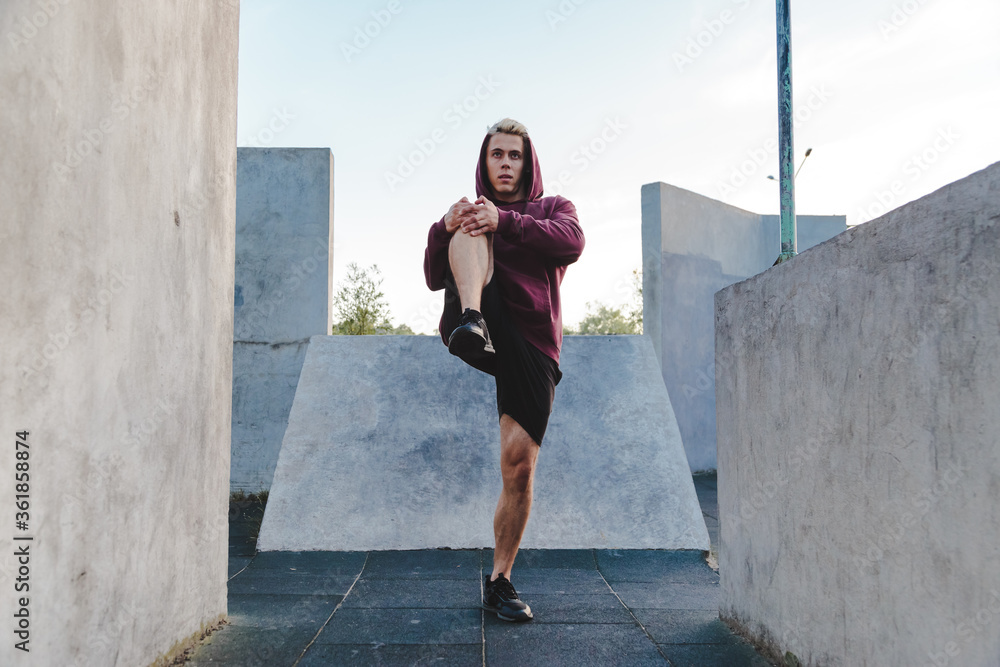 Young caucasian man stretching his legs, warming up for run Young caucasian man stretching his legs, warming up for run