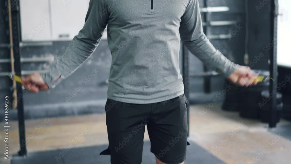 Portrait of active guy jumping with skipping rope in gym training alone enjoying cardio exercise indoors. Modern youth, healthy lifestyle and fitness concept. Portrait of active guy jumping with skipping rope in gym training alone enjoying cardio exercise indoors. Modern youth, healthy lifestyle and fitness concept.