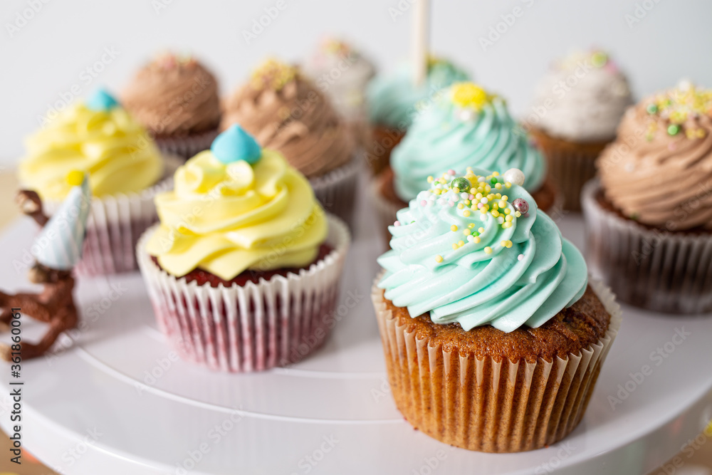 Colorful homemade cupcakes served on a white plate close up still