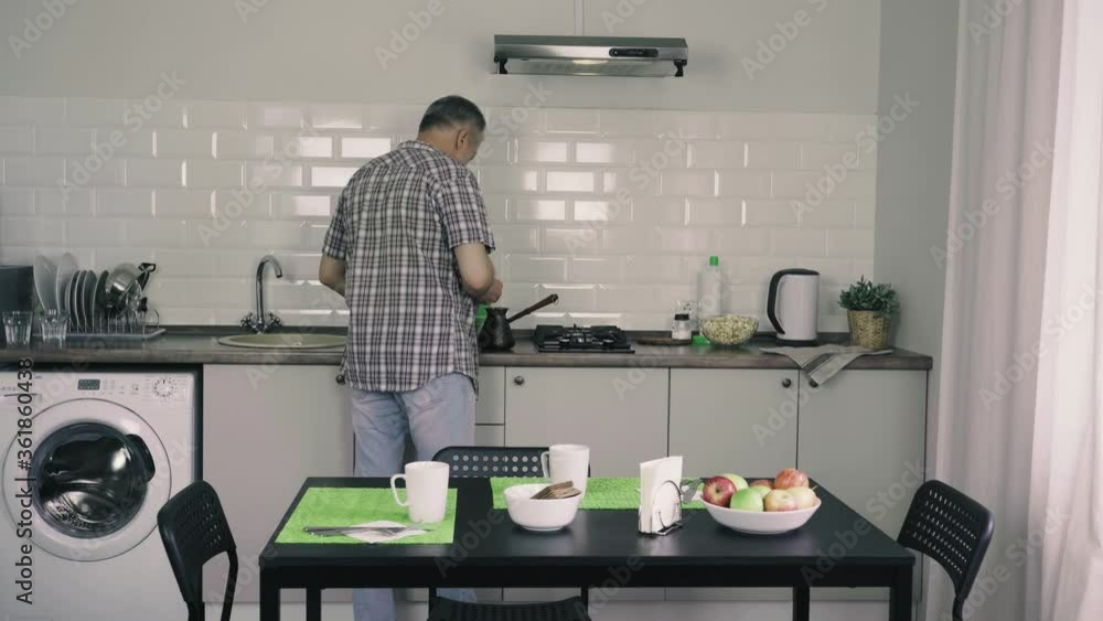 A man makes coffee in the kitchen during the day. A man makes coffee in the kitchen during the day.