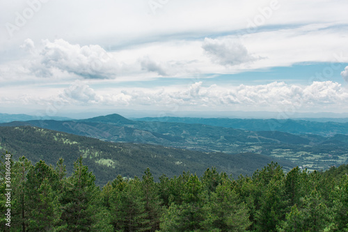 A beautiful view from the mountain. View of the mountain forest, hills and pine trees. Green nature under a beautiful sky with clouds.  © Petar
