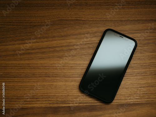 Top down view of iPhone sitting on a fine wood grain desk, either in the office or at home