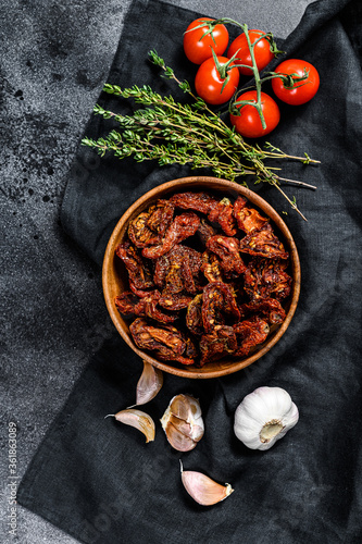 Dried tomatoes with garlic, spices and herbs. Black, dark background. Top view