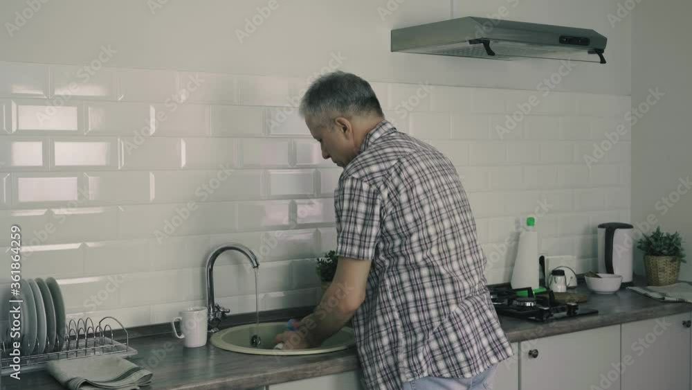 A man washes dishes in the kitchen. A man washes dishes in the kitchen.