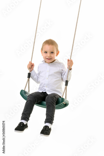 Cute Blond Boy Swinging on Rope Swing and Looking at Camera © lotosfoto