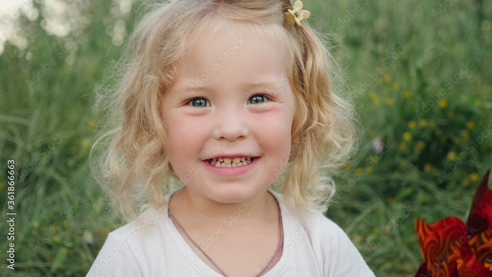 Lovely little girl smiling looking at the camera on nature. Close up little blonde cute girl face. Lovely little girl smiling looking at the camera on nature. Close up little blonde cute girl face.