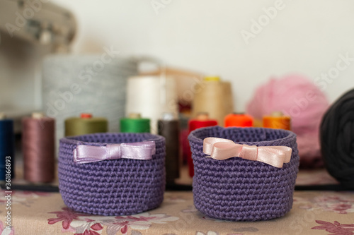Purple knitting basket with ribbon and sewing threads in the background