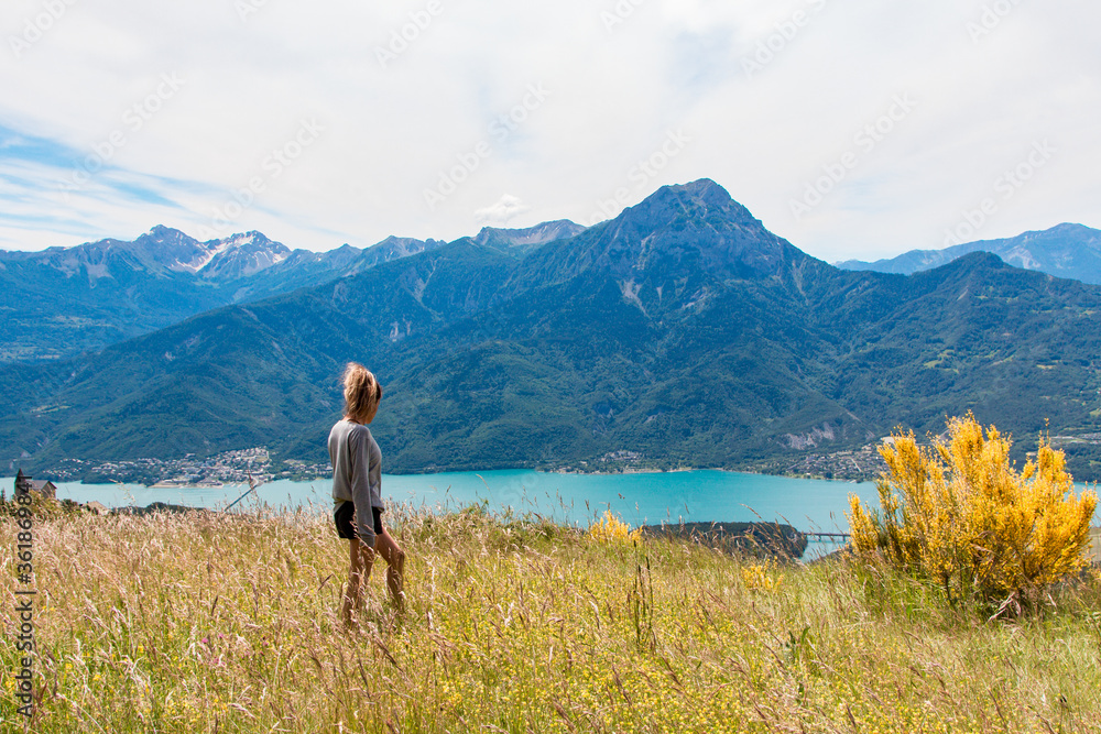 Chica joven contemplando un lago en un entorno de alta montaña.
