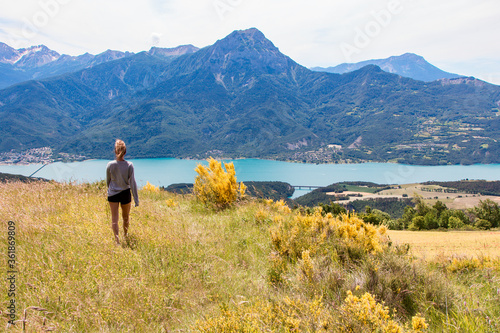 Chica joven contemplando un lago en un entorno de alta montaña.