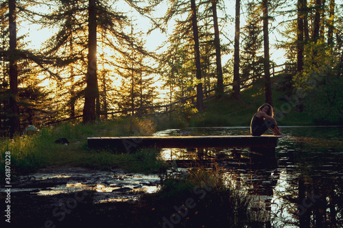 Chica joven en un entorno de naturaleza, bosque y lago, durante la puesta de sol.