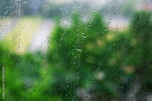 Abstract background. Drops of water on a window on a blurred background of nature.