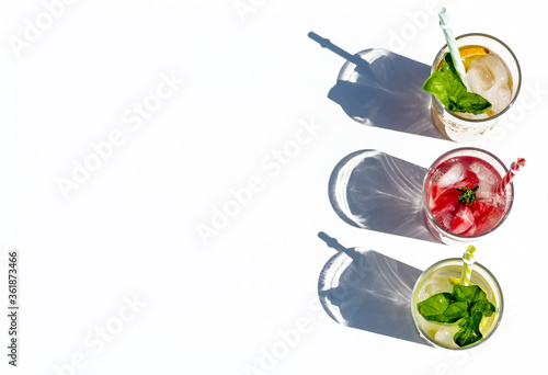 Iced summer drink. Refreshing multicolored alcol-free cocktails in glasses with straws. Watermelon,cucumber, lemon, orange, strawberry cocktail on white background. Top view. Space for text.