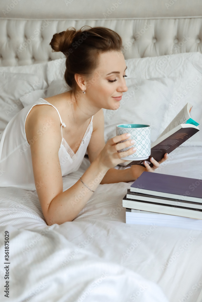 Happy young woomen relaxing on bed and reading book staying at home. Girl learning at home reading literature during quarantine Happy young woomen relaxing on bed and reading book staying at home. Girl learning at home reading literature during quarantine