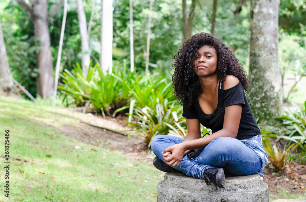 a young black woman between 20 and 30 years old sitting reading a book alone, in a park a young black woman between 20 and 30 years old sitting reading a book alone, in a park
