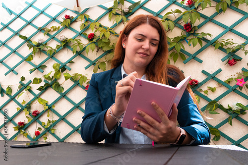 Young girl wearing classy outfit in her garden working from home, chec photo