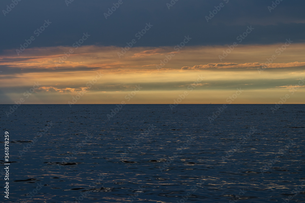 Empty shoot of sunset over sea water, after the thunderstorm. Full of clouds and vibrant colors over horizon. 