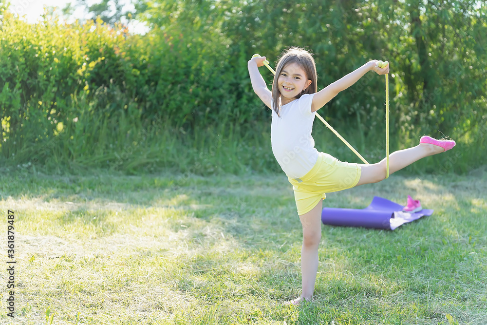 The child goes in for sports in the park. Girl jumping rope The child goes in for sports in the park. Girl jumping rope