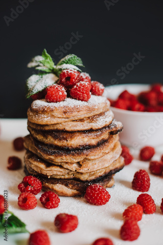 Chocolate pancakes with fresh raspberries and mint on black background
