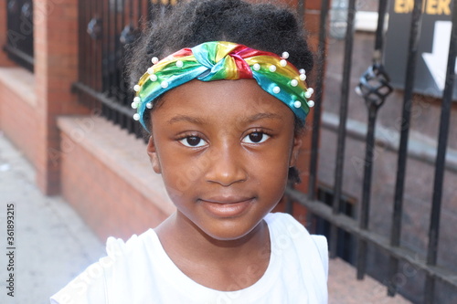 Cute child wearing colorful headband outdoors on city street close up photo
