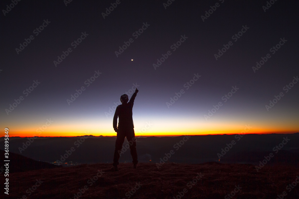 silhouette of man on top mountain at sunset