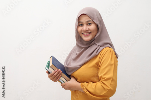 Portrait of young muslim business woman wearing hijab holding book and smiling, educational or leisure activity concept