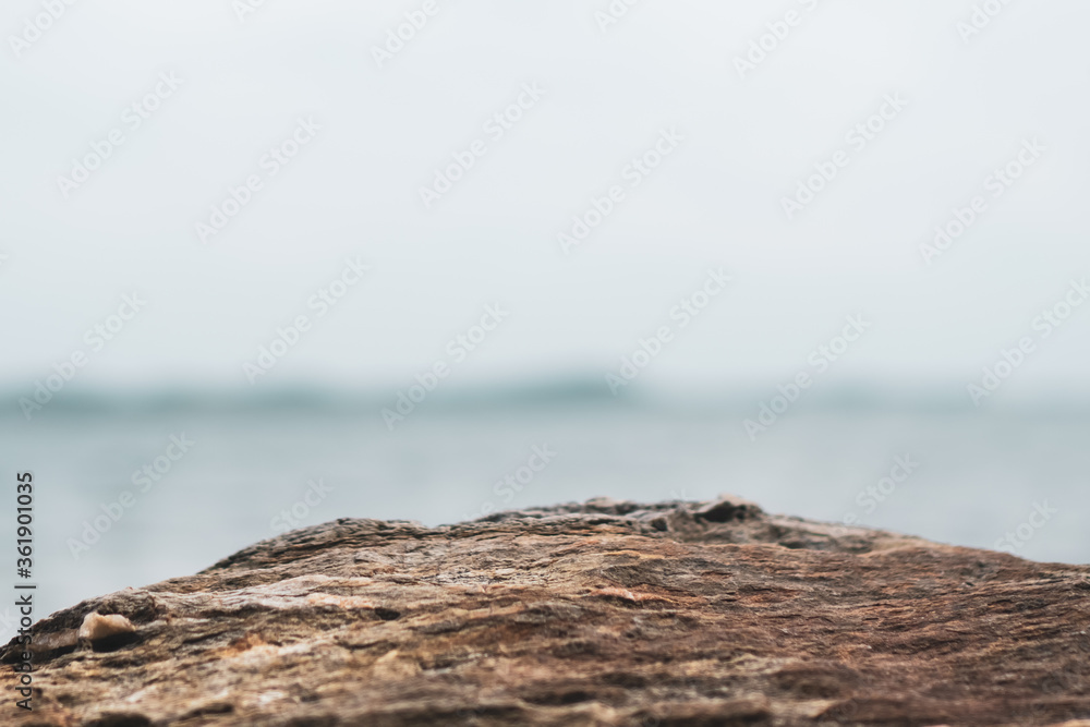 Selective focus od black stone texture for put product to show with beach background. Selective focus od black stone texture for put product to show with beach background.