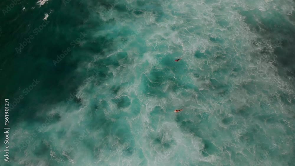 Surfers pedal out in ocean waves. seen from above. Drone aerial shot 4k. Tropical paradise, Hawaii adventure vacation, north shore big waves surf, island travel. Surfers pedal out in ocean waves. seen from above. Drone aerial shot 4k. Tropical paradise, Hawaii adventure vacation, north shore big waves surf, island travel.