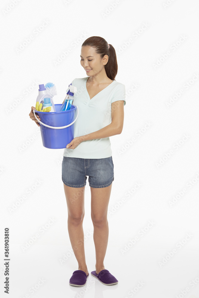 Woman holding a bucket filled with cleaning supplies Woman holding a bucket filled with cleaning supplies