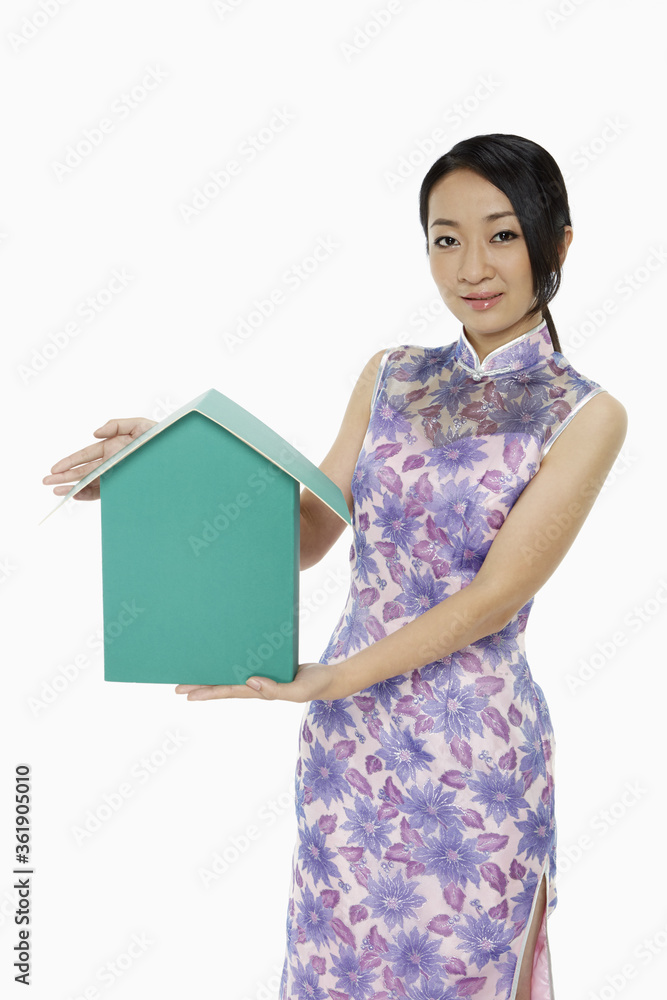 Woman in traditional clothing holding up a cardboard house Woman in traditional clothing holding up a cardboard house