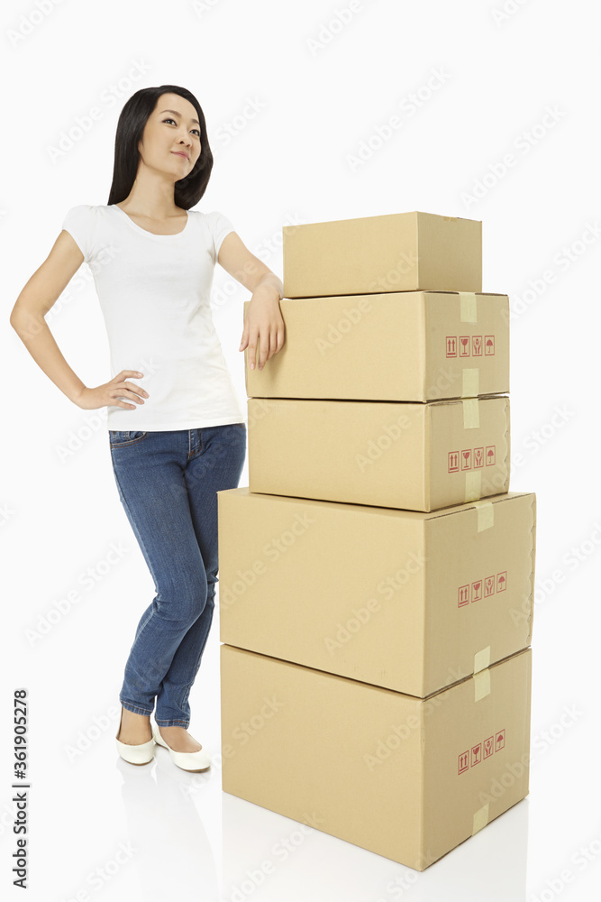 Woman standing beside a stack cardboard boxes Woman standing beside a stack cardboard boxes