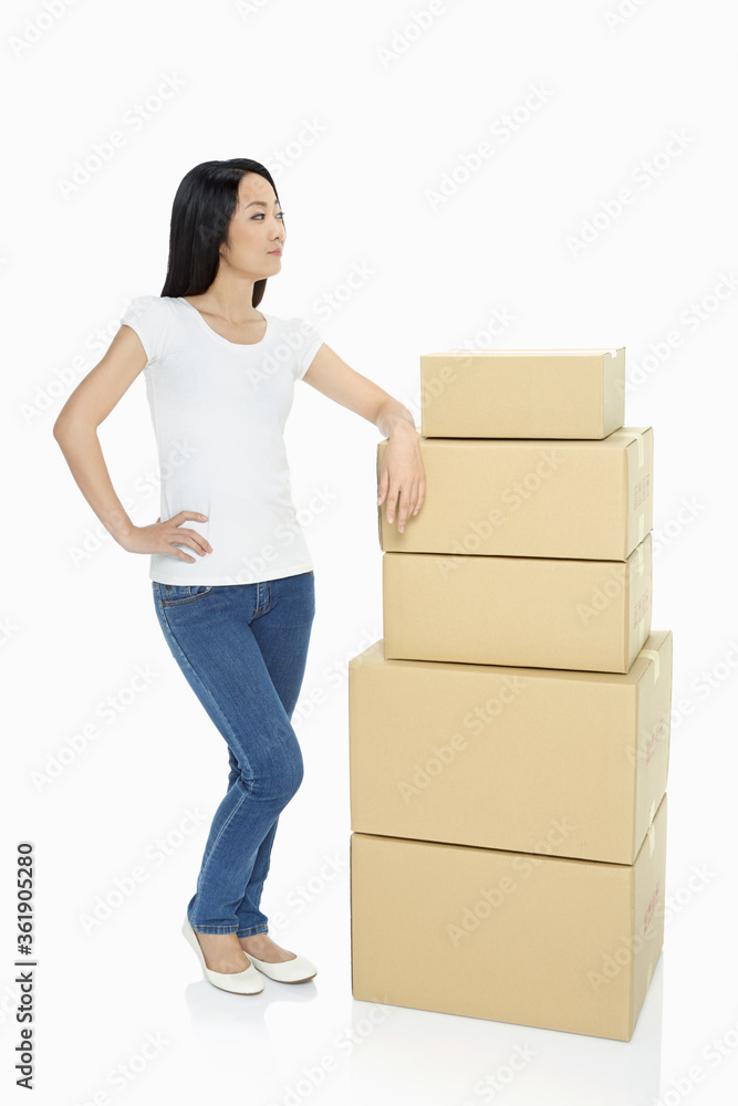 Woman standing beside a stack cardboard boxes Woman standing beside a stack cardboard boxes