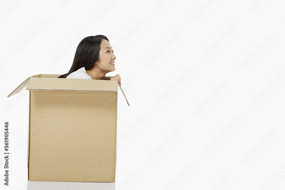 Woman sitting inside of a cardboard box, smiling Woman sitting inside of a cardboard box, smiling