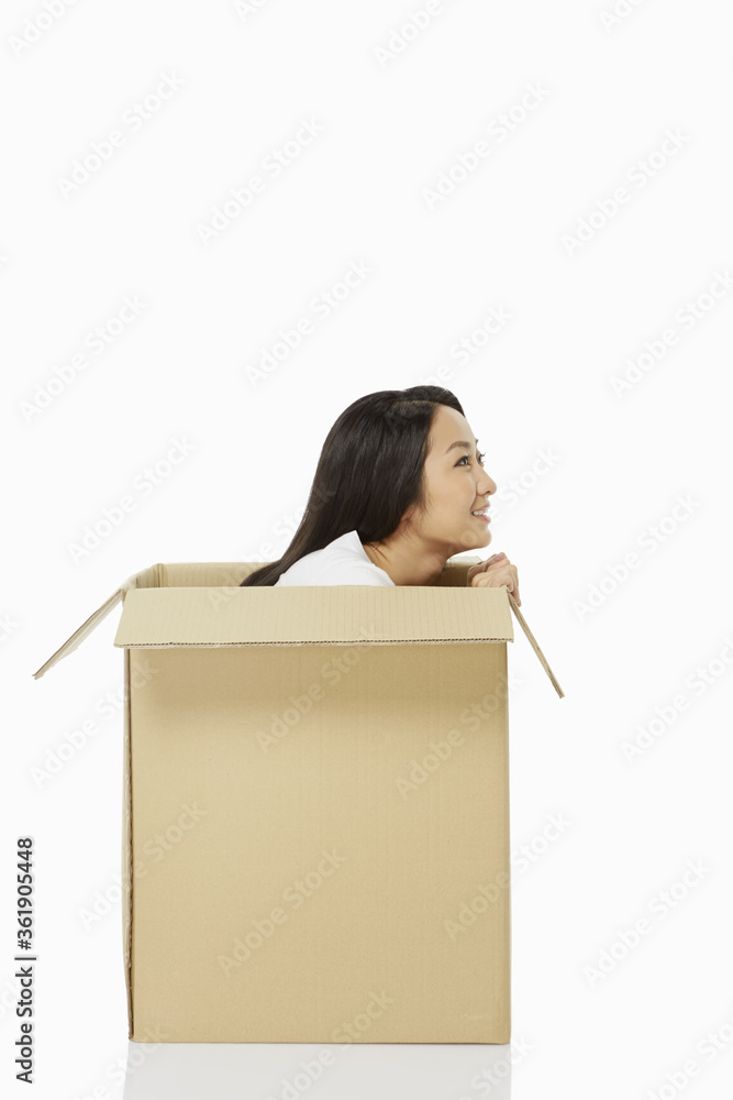 Woman sitting inside of a cardboard box, smiling Woman sitting inside of a cardboard box, smiling