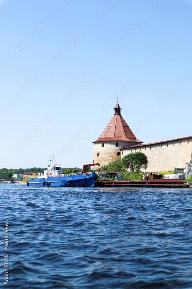 the pier with a ship and medieval Shlisselburg (Oreshek) fortress on the island in Russia