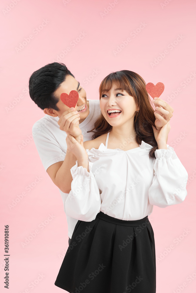 portrait of handsome bearded man closing eyes of his girlfriend by red paper hearts, isolated on pink portrait of handsome bearded man closing eyes of his girlfriend by red paper hearts, isolated on pink