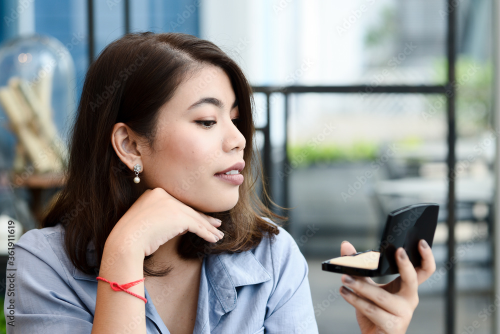 Asian woman looking mirror in a public place. Asian woman looking mirror in a public place.