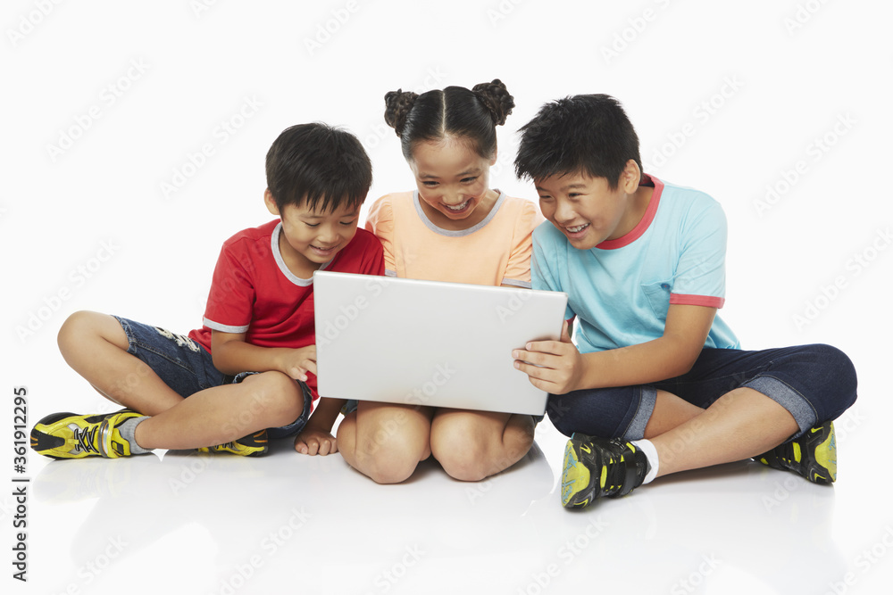 Three children using a laptop together Three children using a laptop together