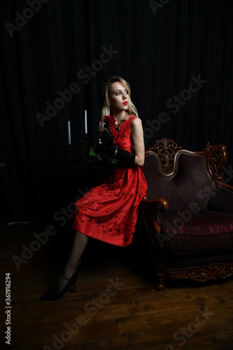 young and beautiful girl in a red dress in a romantic style with a candelabrum
