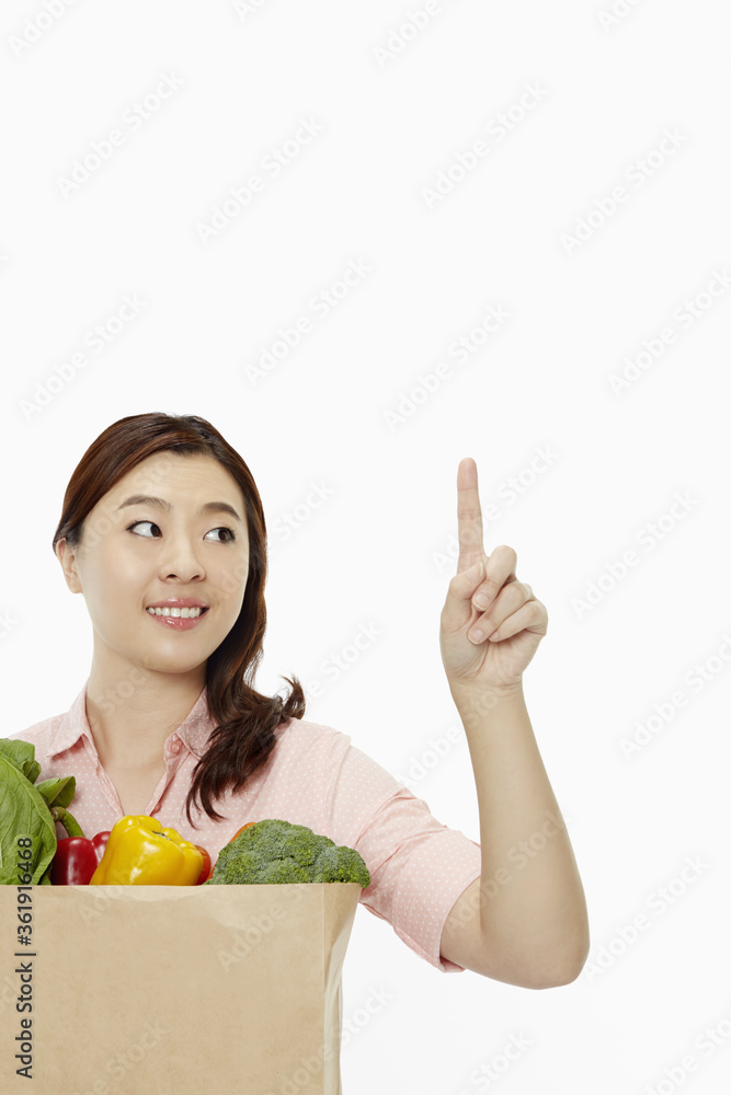 Cheerful woman with groceries showing hand gesture Cheerful woman with groceries showing hand gesture