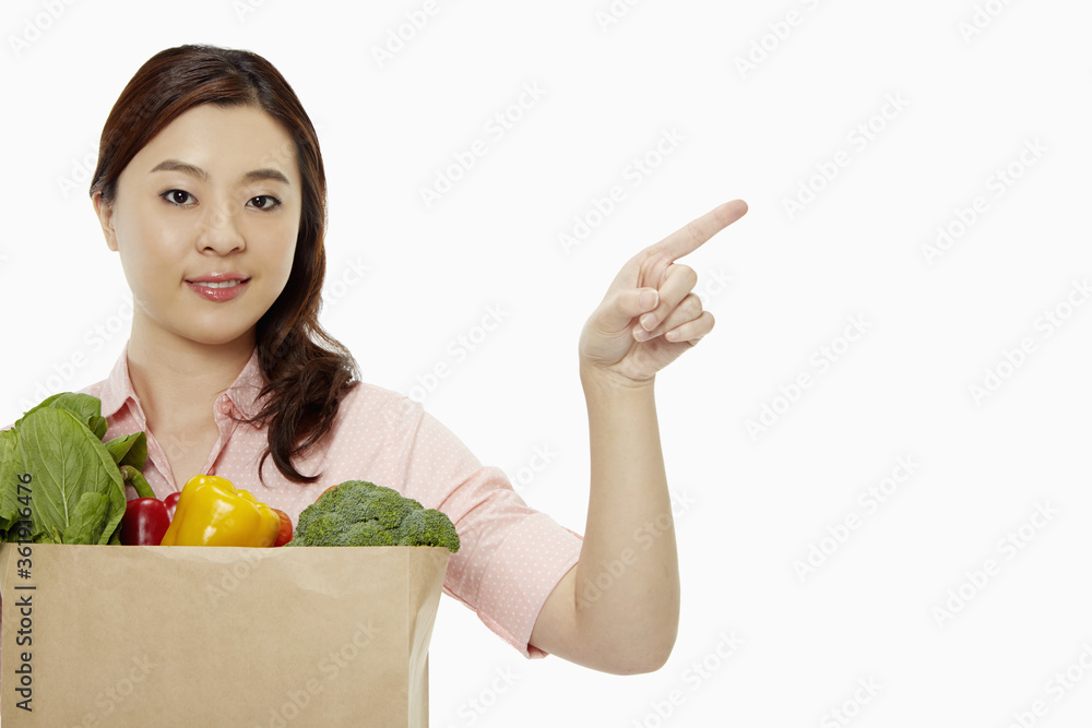 Cheerful woman with groceries showing hand gesture Cheerful woman with groceries showing hand gesture
