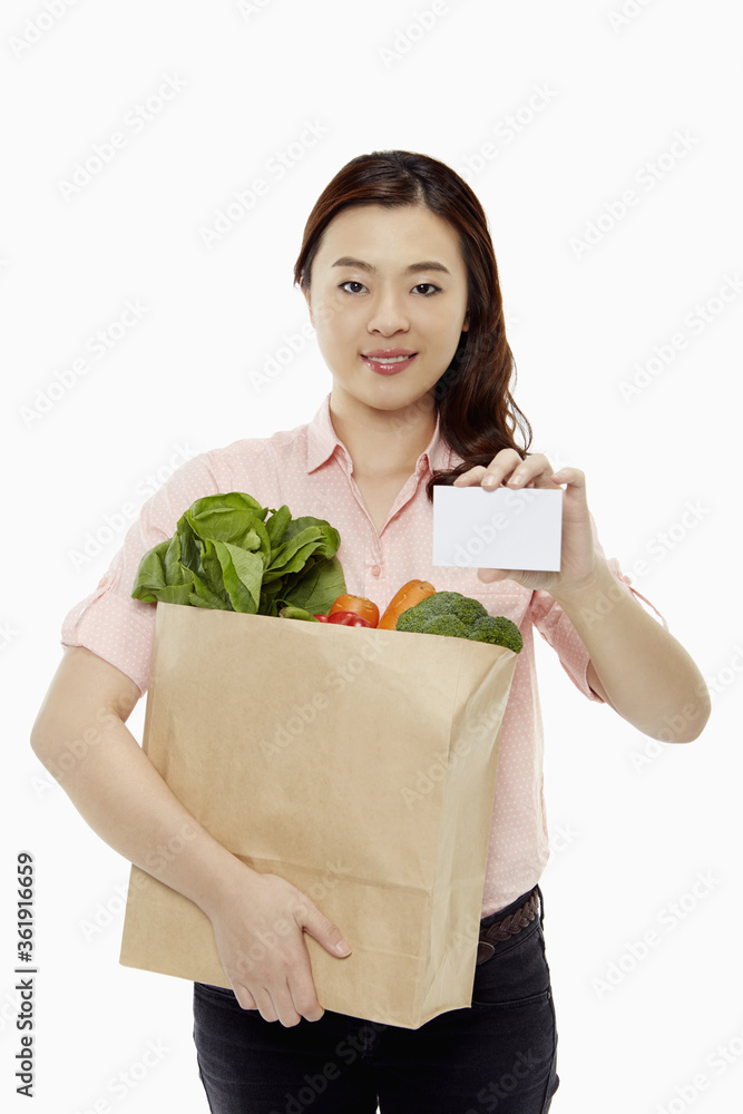 Woman with groceries holding up a blank card Woman with groceries holding up a blank card