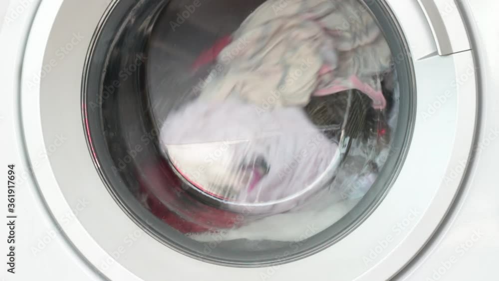 washing machine working with rotating garments inside, process of cleaning cloth with washing machine, laundry concept washing machine working with rotating garments inside, process of cleaning cloth with washing machine, laundry concept