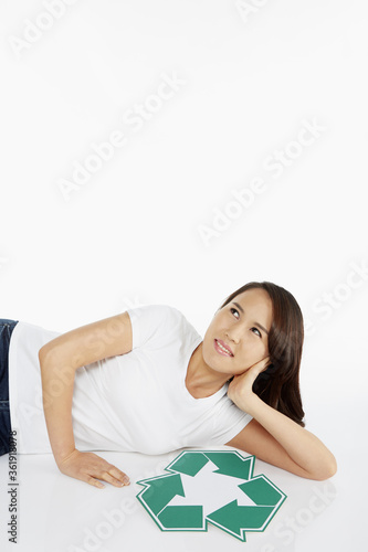Woman lying down beside a Recycle logo