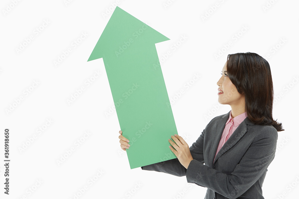 Businesswoman holding an arrow, pointing upwards Businesswoman holding an arrow, pointing upwards