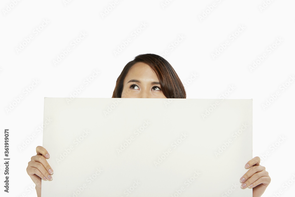 Woman holding up a blank placard, covering mouth Woman holding up a blank placard, covering mouth